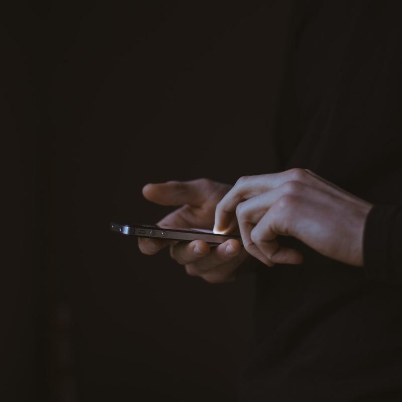 Grafika: telefon trzymany w dłoniach