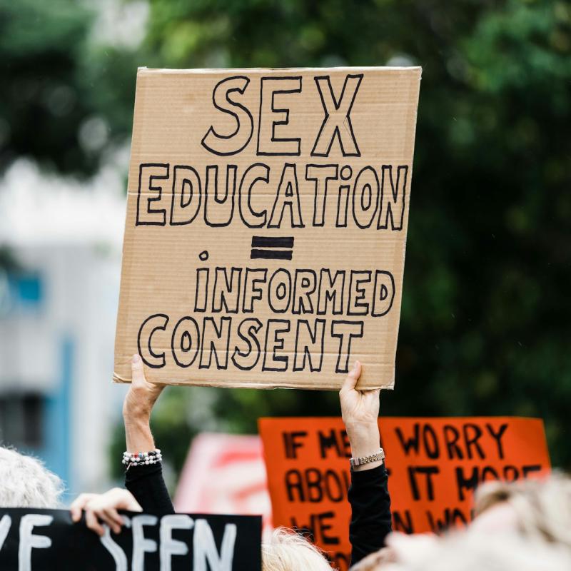 Kobieta trzyma tabliczkę z napisem "sex education = informed consent'